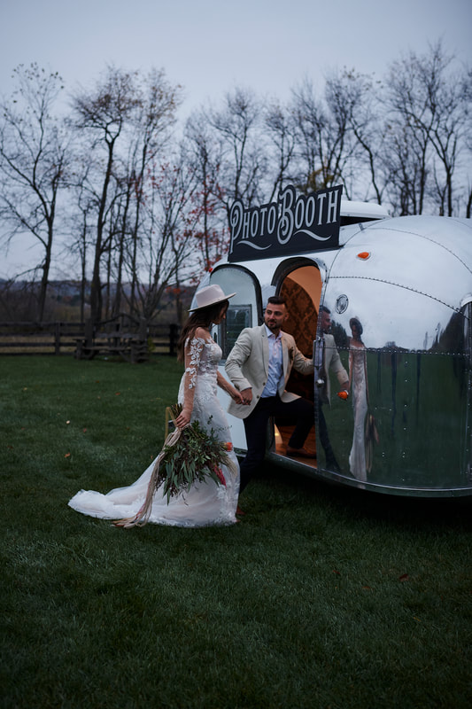 Bride and groom stepping into the vintage Airstream Bambi photo booth